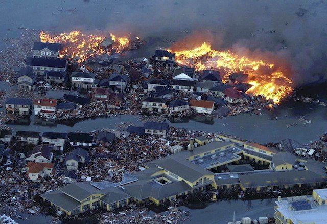 Houses are in flame while the Natori river is flooded over the surrounding area by tsunami tidal waves in Natori city, Miyagi Prefecture, northern Japan, March 11, 2011, after strong earthquakes hit the area. 